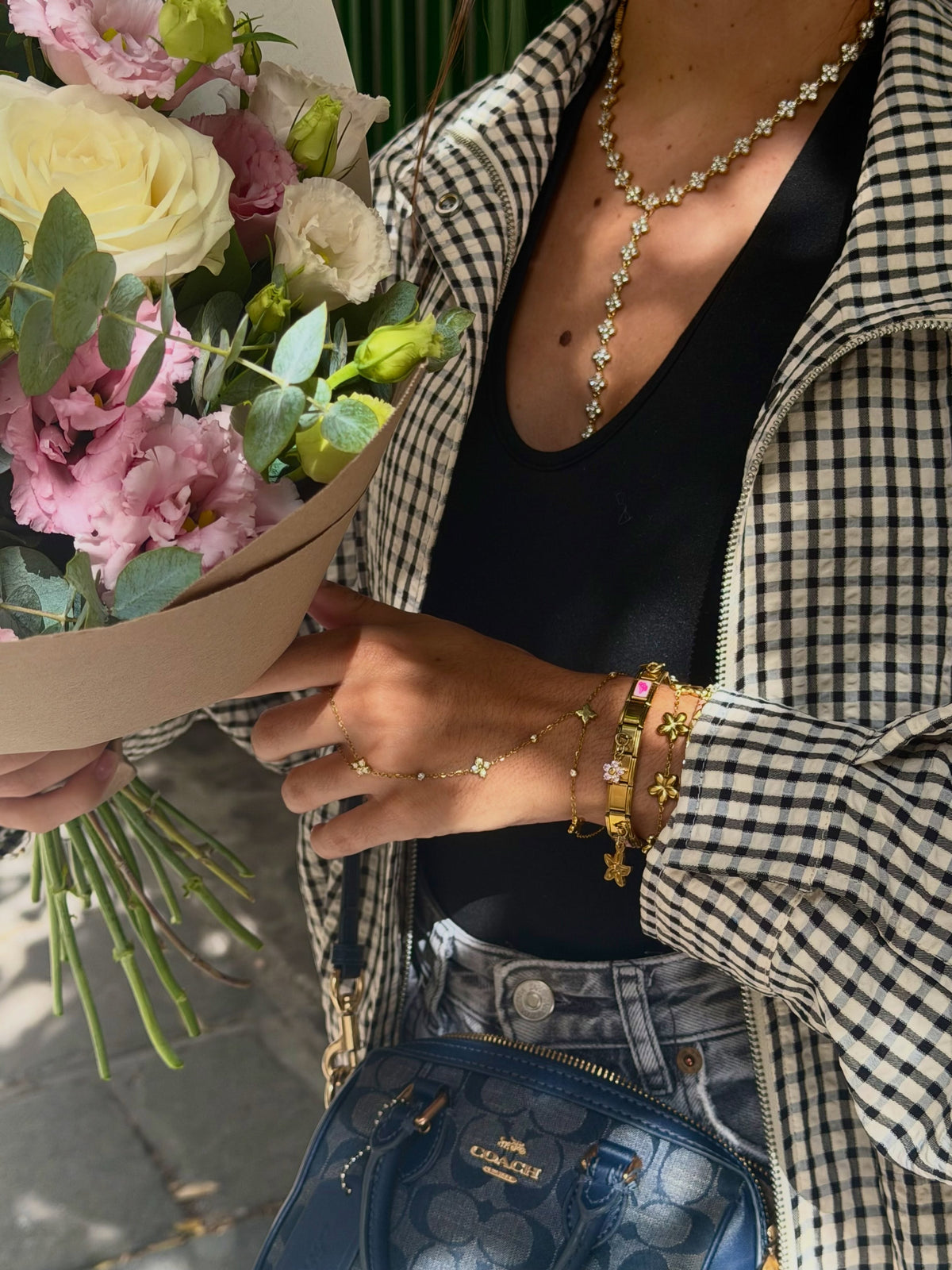 Poignet portant des bracelets à charms italiens dorés, tenant un bouquet de fleurs